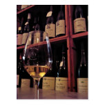 Copa de vino con las botellas en fondo postales