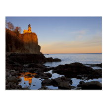 Faro partido de la roca en la puesta del sol cerca tarjetas postales