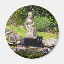 Gato negro debajo de la estatua en jardín verde imán para frigorifico