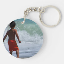 muchacho en la playa que juega en agua llavero