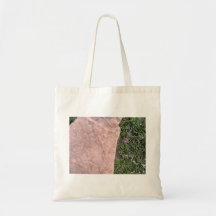 Roca de piedra roja aislada en paisaje verde bolsa de mano