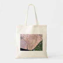 Roca roja agrietada en paisaje verde bolsas de mano
