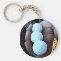 Tres pelotas de golf en manos ásperas, sucias llaveros