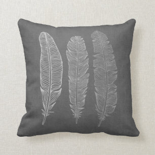 3 plumas en la almohada gris