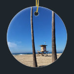 Adorno De Cerámica Blackies, Newport Beach, California<br><div class="desc">Vista del famoso spot de surf "Blackies" desde el aparcamiento en Newport Beach, California. La torre de vigilancia 22 entre dos palmeras. En 1953, William "Blackie" Blackstock abrió el bar de buceo Blackies by the Sea. Desde entonces, los lugareños han llamado a esta playa "Blackies", y es un popular sitio...</div>