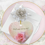 Adorno De Cerámica Corazón de compromiso de rosa rosa<br><div class="desc">Elegante adorno de conservas de cerámica "cases me" (cásese conmigo) presenta una simple rosa rosa rosada en un agua de color nítido de fondo rosa con gotas de agua. Accesorio perfecto para una propuesta de matrimonio antes de elegir anillos. Simplemente edite el texto delante y atrás en el sencillo editor...</div>