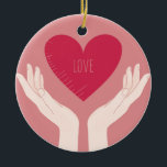 Adorno De Cerámica El corazón rojo ama al El día de San Valentín romá<br><div class="desc">diseño romántico de un corazón rosa brillante con la palabra amor en el medio y dos manos sosteniendo el corazón contra un fondo rosa rubor. Este bonito diseño elegante de chicas es perfecto para el día de San Valentín o cualquier otra ocasión romántica.</div>