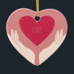 Adorno De Cerámica El corazón rojo ama al El día de San Valentín romá<br><div class="desc">diseño romántico de un corazón rosa brillante con la palabra amor en el medio y dos manos sosteniendo el corazón contra un fondo rosa rubor. Este bonito diseño elegante de chicas es perfecto para el día de San Valentín o cualquier otra ocasión romántica.</div>