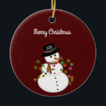 Adorno De Cerámica Feliz Navidad a Snowman personalizado<br><div class="desc">El muñeco de nieve lindo está enredado con luces de Navidades iluminadas, tiene el año en su gorra - el texto de "Feliz Navidad" de arriba puede ser cambiado o agregado, y el estilo/tamaño del tipo de letra también puede ser cambiado. Se muestra en un fondo rojo profundo, que puede...</div>