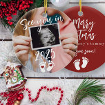 Adorno De Cerámica Feliz Navidad te veo en el embarazo fotográfico de<br><div class="desc">Moderno y gracioso nos vemos en el guión de 2025,  huellas y recienes nacidos de corazones rojos esperando a los padres que aguantaran la Feliz Navidad del árbol rojo de barriga de mamá adornado con la foto de su personalizado.</div>