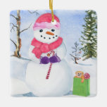 Adorno De Cerámica Hombre de nieve con pañuelo rosa y bastón de caram<br><div class="desc">Hombre de nieve con una bufanda rosa y con un bastón de caramelo. Paisaje invernal y una bolsa de regalo en verde lima con un oso y un chupete al lado del muñeco de nieve. Al fondo, tu nombre, el año y los días de nieve feliz pueden ser personalizados. Acuarela....</div>