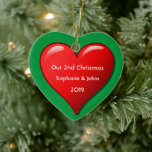 Adorno De Cerámica Nuestros segundos Navidades juntos cortan el coraz<br><div class="desc">Nombres personalizados e impresos con un bonito diseño de corazón rojo en un fondo verde sólido. Siéntete libre de personalizar añadiendo tus propios textos,  nombres o fotos. ¡Puedes añadir tu foto en la parte posterior del adorno fácilmente! El color del fondo también se puede cambiar como se desee.</div>