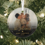 Adorno De Cristal Black Gold Script Family Photo Merry Christmas<br><div class="desc">Elegante nombre de familia Minimalista negra y dorada y texto "Feliz Navidad". Incluye tu foto familiar favorita, con el guión caligráfico escrito a mano "nombre de familia", texto "Feliz Navidad", pequeño motivo cardíaco y año en negro y oro (superposición de foto degradado negro). Fácil de personalizar. Consejo de la foto:...</div>