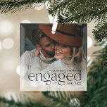 Adorno De Cristal Nuestra primera foto personalizada de Navidad<br><div class="desc">Un elegante recuerdo de su año de compromiso,  este hermoso adorno de vidrio muestra una foto favorita con "nuestra primera Navidad enganchada" cubierta con letras azul marino oscuro acentuadas con estrellas. Personaliza con tus iniciales y el año.</div>