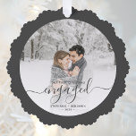 Adorno De Papel Primer guión gris de la foto de Personalizado comp<br><div class="desc">Conmemorar su compromiso con esta hermosa tarjeta de adorno de keepsake. El texto gris del carbón dice "Nuestra primera Navidad comprometida", con la palabra "comprometida" en un elegante guión de escritura a mano con flores antes y después. Reemplace la imagen de ejemplo con su foto favorita y agregue sus nombres...</div>
