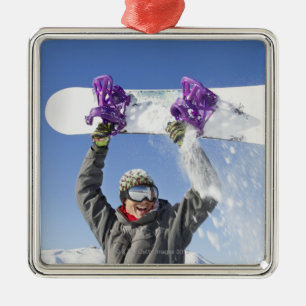 Adorno Metálico Hombre joven que sostiene su snowboard sobre su