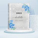 Agenda Cita de nombre floral azul plateado 2024<br><div class="desc">Un falso fondo metálico plateado,  con flores azules olvidadas no,  flores. Polvo falso purpurina. Personalice y agregue un año,  nombre y título.</div>