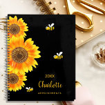 Agenda Monograma girasol abejas lindas negro<br><div class="desc">Un color de fondo negro de moda. Decorada con grandes girasoles de color acuático y 3 bonitas y alegres abejas sonrientes. Personalice y agregue un nombre, año y título. El nombre está escrito en negro con un gran guión moderno de estilo con letras a mano. Perfecto para la escuela, el...</div>