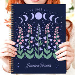 Agenda Nombre personalizado de Moonlit Phase Garden 2025<br><div class="desc">Escape a un jardín iluminado por la luna donde los sueños florecen bajo el resplandor celeste. Este encantador planificador, adornado con fases lunares y flores florecientes, le invita a planificar su año bajo las estrellas. Imagínate anotando tus aspiraciones y citas en medio de esta tranquila escena nocturna. Personalízalo con tu...</div>