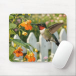 Alfombrilla De Ratón Hummingbird with Touch-Me-Not Flower<br><div class="desc">A hummingbird,  its iridescent feathers shimmering in the sunlight,  hovers by a bright orange touch-me-not flower in a lush garden framed by a white picket fence</div>