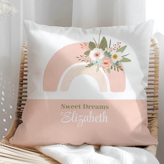 Almohada con nombre personalizado arcoiris rosa fl (Floral Pink Rainbow Custom Name Pillow on a sunny rattan chair.)