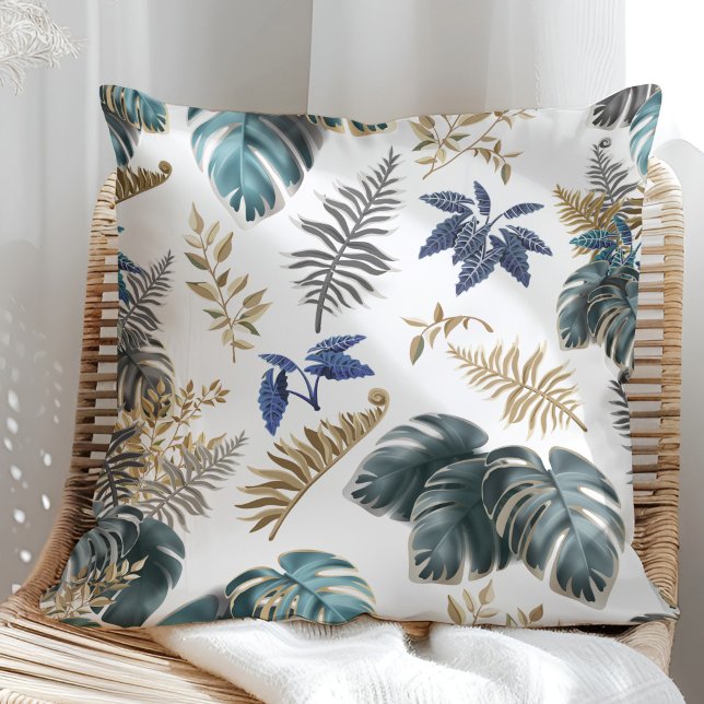 Almohada con patrón de hojas azul tropical y dorad (Tropical Blue and Golden leaves Pattern Pillow in a sunny rattan armchair.)