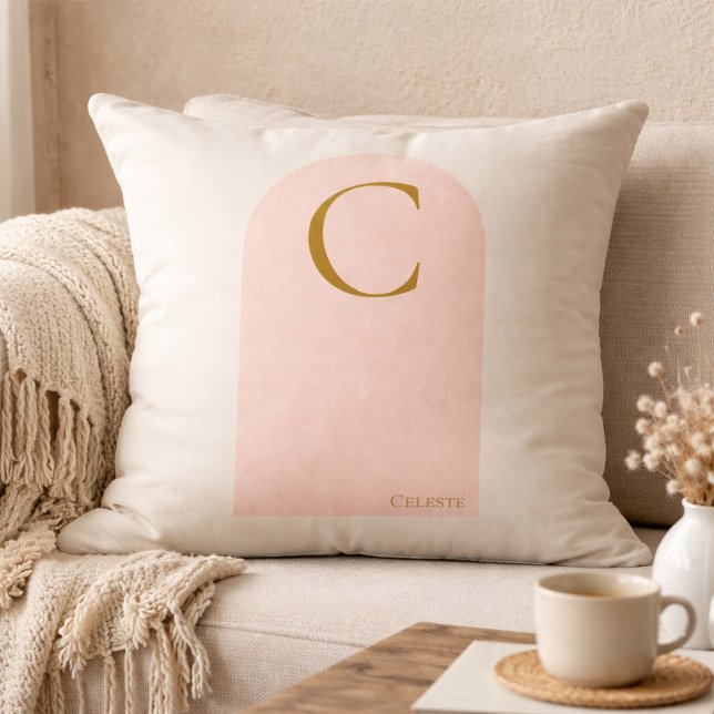 Almohada de tirar con monograma de arco sonrosado (Soft ivory meets blush arch detail, finished with a gold serif monogram for refined neutral living.)