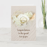 Anillos de boda en la tarjeta de arena y conchas