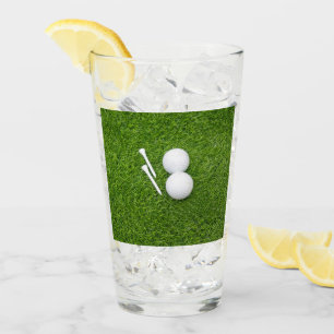 Balón de golf y tee sobre césped verde