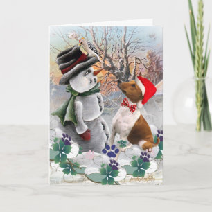 Basenji mira tarjetas del muñeco de nieve