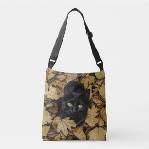 Bolso Cruzado Un gato negro está jugando en las hojas de otoño