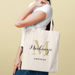 Bolso De Tela Dama de honor con monograma negro y oro elegante<br><div class="desc">El glamour atemporal se une a la elegancia clásica en este bolso tote que presenta una inicial de monograma dorado superpuesta con un nombre personalizado en elegante letra negra y el rol en la fiesta de bodas debajo. Un recuerdo de monograma de lujo con un cálido brillo dorado que eleva...</div>