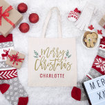 Bolso De Tela Modern Gold Script Merry Christmas Custom Name<br><div class="desc">El elegante diseño de la bolsa de tote de Feliz Navidad presenta ramas verdes festivas de hojas huecas y bayas rojas acentúan el moderno diseño de escritura de oro antiguo. El texto del monograma del personalizado puede personalizarse un nombre u otro texto.</div>