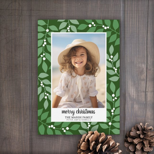 Borde botánico con guión gráfico Feliz Navidad (A berry botanical holiday card in shades of green leaves and white berries. 1 Photo)