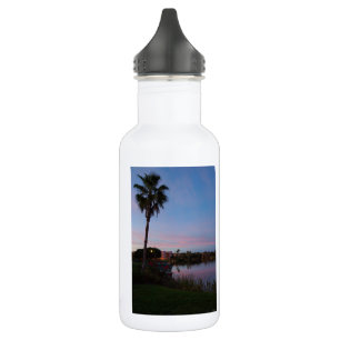 Botella de agua de la tarde junto a la palmera
