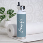Botella De Agua Elegante mujer de escritura azul turquesa<br><div class="desc">Manténgase hidratado durante su entrenamiento en el gimnasio con esta elegante botella de agua de guijarros blancos y azul. Es moderno y de diseño, con un fondo azul a la moda alrededor de la botella. El nombre está en la letra del guión de la mano blanca vertical en el frente...</div>