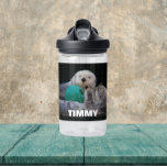 Botella De Agua Las nutrias marinas con el nombre del niño<br><div class="desc">Botella de agua de plástico transparente del tamaño de un niño que muestra la foto de un par de nutrias de mar jugando con un juguete de bolas junto con el nombre de un niño impreso en letras blancas y negrita. Personalice la botella de agua editando el nombre y reemplazando...</div>