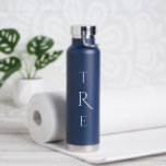 Botella De Agua Monograma de moda sobre azul<br><div class="desc">El monograma vertical blanco de moda sobre azul presenta una inicial más decorativa en el centro. Reemplace las 3 iniciales por las suyas en la barra lateral. En la barra lateral se pueden encontrar otros colores y estilos para botellas de agua. Copyright © Claire E. Skinner. Todos Los Derechos Reservados....</div>