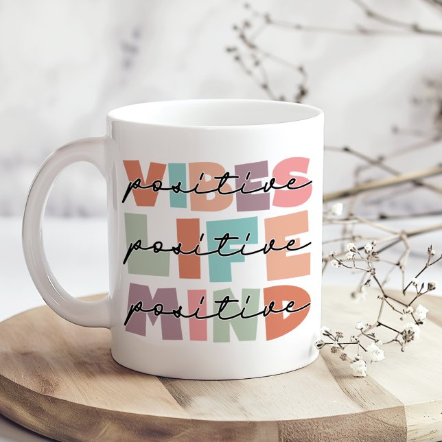 Café Taza con tipografía estética de mente positiva (Positive Vibes Positive Life Inspirational Coffee Mug on a boho kitchen table with tiny white flower)