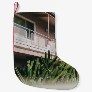 CALCETÍN NAVIDEÑO PEQUEÑO PLANTA VERDE DE COLOR ROSADO CERCA DEL EDIFICIO