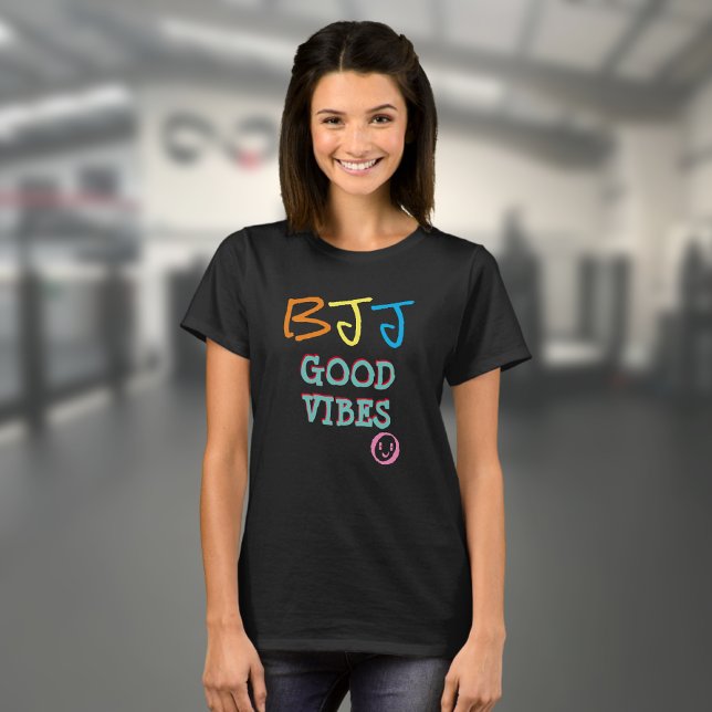 Camiseta BJJ Retro Graffiti estilo Buenas vibraciones Negro (Black BJJ Good Vibes T shirt worn by a female model in a gym)