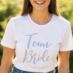 Camiseta Boda de nombres personalizados de novia Dusty Blue<br><div class="desc">Celebra tu Bride Squad con estilo con esta camiseta boda personalizada de moda! Con la frase "Novia en equipo" en una fuente de script elegante, esta plantilla se puede personalizar con un nombre, fecha de boda, ubicación o cualquier texto que elija. Perfecto para fiestas de soltera, duchas de novias, o...</div>