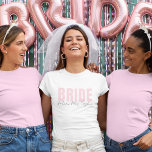 Camiseta Bride T-Shirt | Personalized Future Mrs. Name<br><div class="desc">This modern and personalized Bride T-Shirt is the perfect outfit for any bride-to-be! Featuring soft blush pink “BRIDE” text paired with elegant handwritten “future Mrs. [Your Name]” below, this tee is ideal for bridal showers, bachelorette parties, wedding prep, and honeymoon travel. Available in multiple styles and fits for every bride’s...</div>