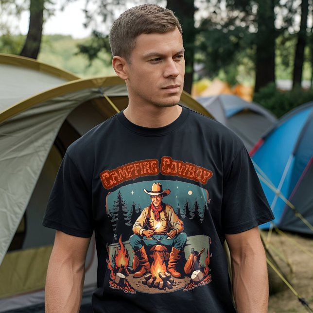 Camiseta Cowboy occidental grafhic del catarro retro (A man wearing a black t-shirt with a "Campfire Cowboy" graphic design, standing in front of a camp)