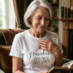 Camiseta Grandma Est Year Minimalist Elegant Script Design<br><div class="desc">This shirt displays the phrase “Grandma Est Year” in a delicate handwritten style. The simple lettering celebrates the joyful moment of becoming a grandmother. The year text can be edited so the date reflects when this special chapter begins. The minimalist design creates a timeless and elegant look.</div>