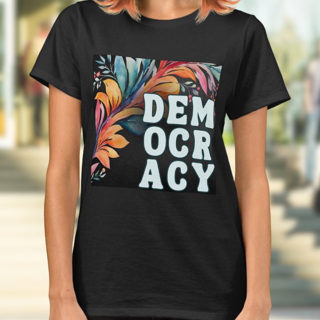 Camiseta Groovy Retro Colorosa Declaración Democracia (A t-shirt with 'Democracy' in capital letters in a retro groovy style, on a colorful leafy backdrop)