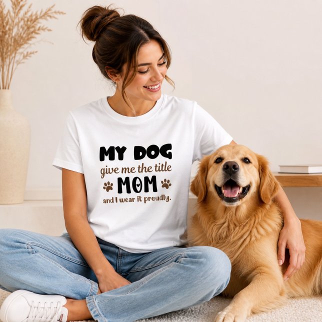Camiseta Mi Perro Me Dio el Título Mamá Lo Llevo con Orgull ( A smiling woman with her Golden Retriever wearing a "Dog Mom" graphic t-shirt.)