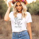Camiseta Novia a Ser Guion Caligrafía Nombre<br><div class="desc">Celebra a la novia con esta hermosa camiseta de caligrafía con letra "Novia a Ser" en tipografía manuscrita fluida y un primer nombre personalizable. Un hermoso monograma para guardar como recuerdo para fiestas de compromiso, despedidas de soltera y fines de semana de soltera. Edita el nombre para personalizar para la...</div>