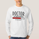 Camiseta Progreso del médica, por favor, espere a la divert<br><div class="desc">Camiseta divertida para el estudiante de medicina. El texto dice: "Médica en progreso. Por favor,  espere". Idea de regalo perfecta para que el estudiante de premedicina o de medicina en formación sea un médico.</div>
