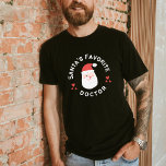 Camiseta Santa's Favorite Doctor: Cute Santa Christmas Tee<br><div class="desc">Celebrate the season with this exclusive Christmas tee for doctors! 
Featuring an adorable Santa and the heartwarming message 'Santa's Favorite Doctor, ' this shirt combines holiday charm with medical pride. 
Perfect for doctors who bring warmth and care to the season.</div>